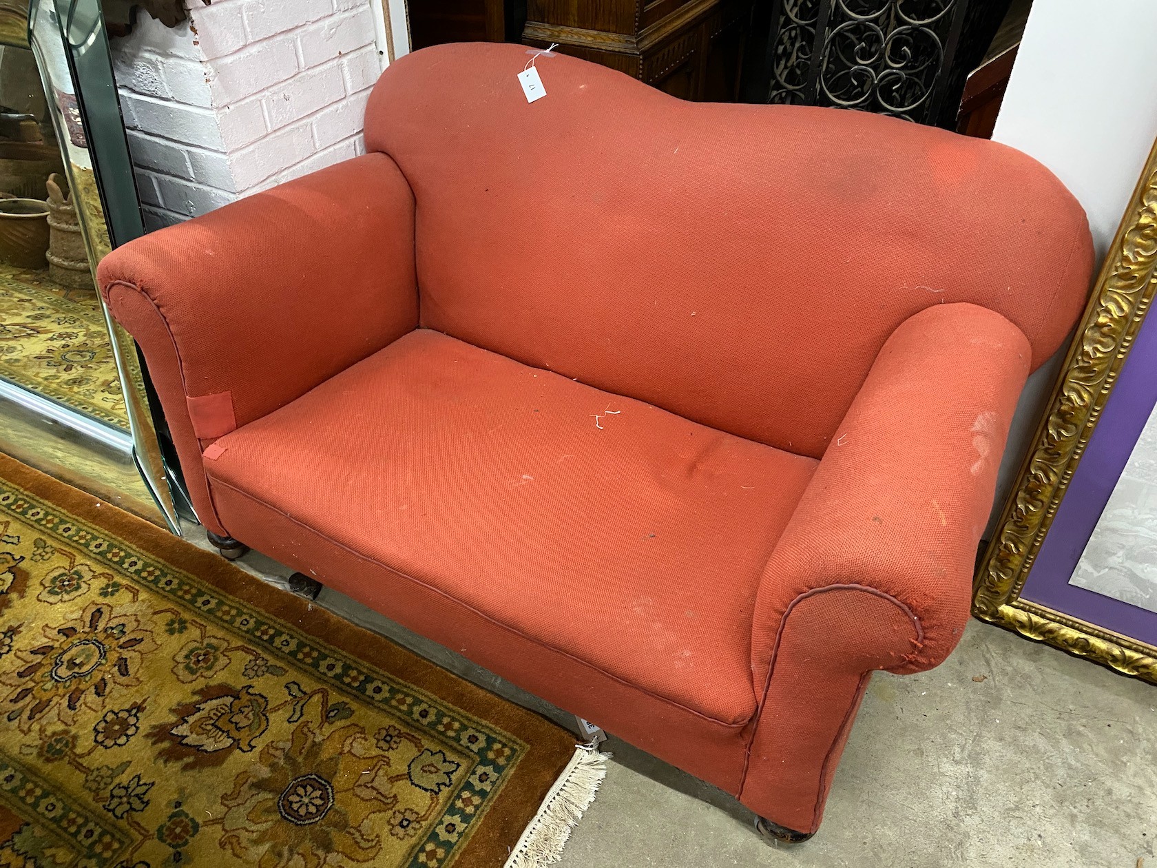 A 1920's upholstered drop arm two seater Chesterfield settee, width 134cm, depth 81cm, height 82cm